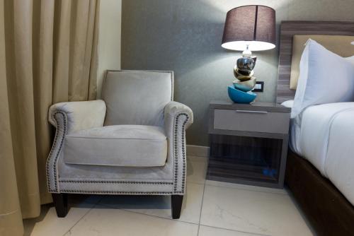 a bedroom with a chair and a bed and a lamp at The Palms by Eagles in Takoradi