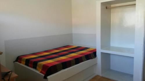 a small room with a bed with a striped blanket at Chalés Praia do Frances in Praia do Frances