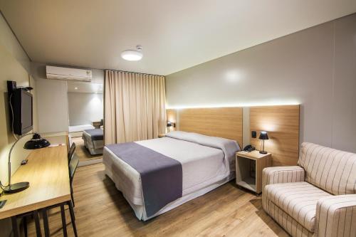 a hotel room with a bed and a couch at JR Hotel in Presidente Prudente