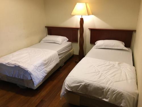two beds in a room with a lamp on the wall at Ian's Vacation Rental in Skudai