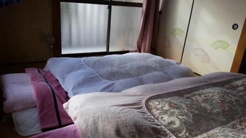 an unmade bed in a room with a window at "Cherry House" is Direct to Narita,Haneda AP, Disney, Asakusa, Skytree Tower, Tokyo in Matsudo