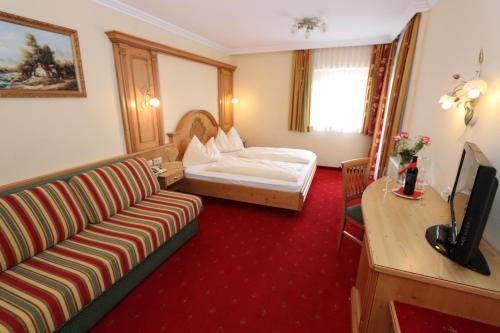 une chambre d'hôtel avec un canapé et un lit dans l'établissement Gasthof Bacher, à Katschberghöhe