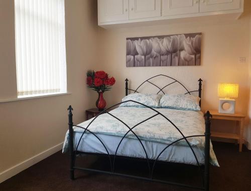 a bedroom with a bed and a vase of red roses at Blackpoolholidaylets Vicarage Lane in Blackpool