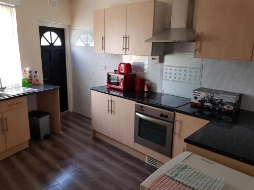 a kitchen with wooden cabinets and a red appliance at Blackpoolholidaylets Vicarage Lane in Blackpool