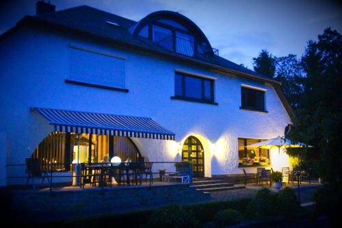 a large white building with tables and chairs at night at Les Alisiers in Nadrin