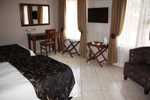 a hotel room with a bed and a chair and a table at Eagles Nest Lodge in Johannesburg