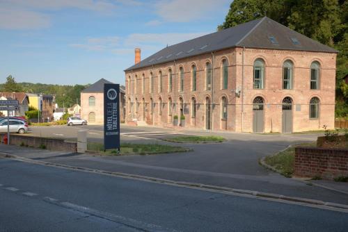 a large brick building with a sign in front of it at Hôtel de la Tabletterie in Méru