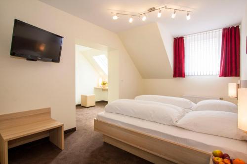 a bedroom with a large bed and a flat screen tv at Hotel Alt Westerholt in Herten