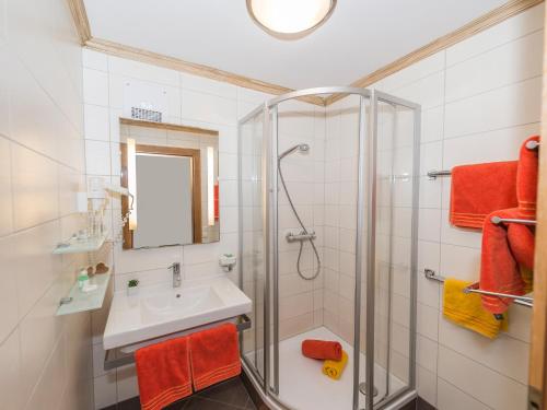 a bathroom with a shower and a sink and a mirror at Appartementhaus Renate in Rauris