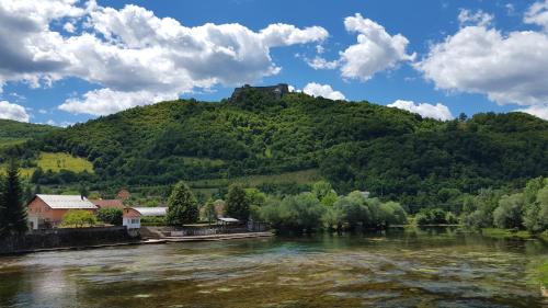 a castle on top of a hill next to a river at Apartment Sajra in Kulen Vakuf