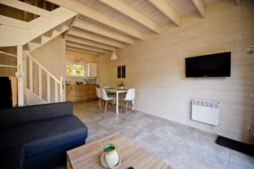 a living room with a couch and a tv on a wall at Domki Na Brackiej in Pobierowo