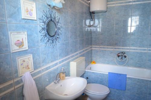 a blue tiled bathroom with a toilet and a sink at Apartman 1 in Podstrana