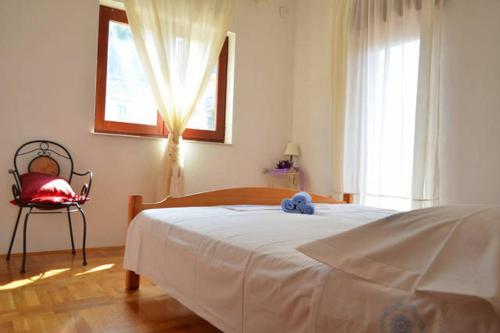 a bedroom with a white bed and a window at Apartman 1 in Podstrana