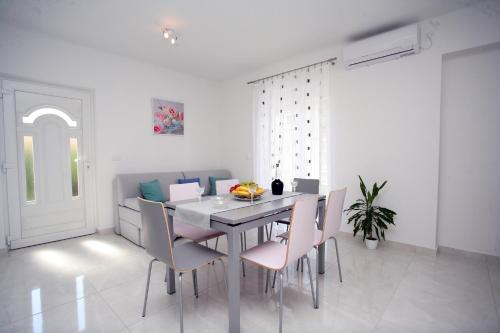 ein Esszimmer mit einem Tisch und rosa Stühlen in der Unterkunft Apartman Fantasy in Trogir