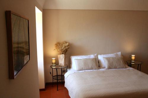 a bedroom with a bed with white sheets and two side tables at Convento di San Colombo in Santo Stefano di Sessanio