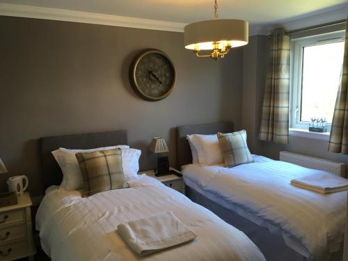 a bedroom with two beds and a clock on the wall at The Huntingdon in Dumfries