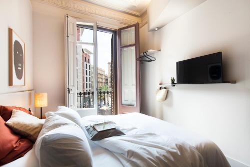 a person laying on a bed in a room with a window at DestinationBCN - Universitat Rooms in Barcelona