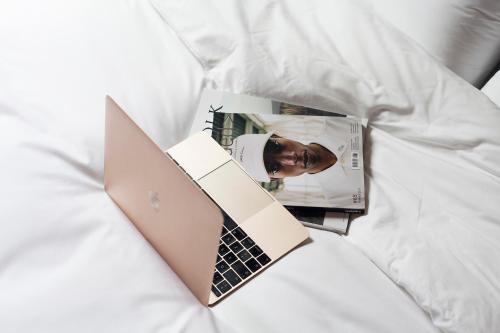 a laptop computer sitting on a bed next to a magazine at DestinationBCN - Universitat Rooms in Barcelona