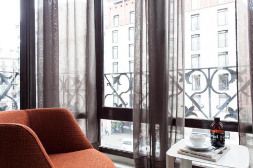 an orange chair sitting in front of a window at DestinationBCN - Universitat Rooms in Barcelona