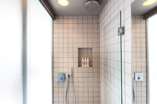 a shower in a bathroom with white tiles at DestinationBCN - Universitat Rooms in Barcelona