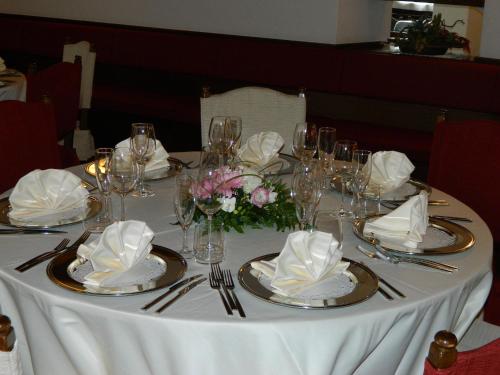 a white table with plates and napkins and flowers on it at Hotel Baita Clementi in Bormio
