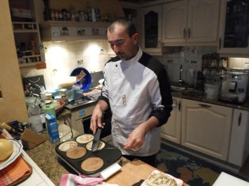 een man in een keuken die eten klaarmaakt in een pan bij Les Volets Bleus Alsace Vosges in Urbès