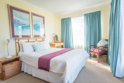 a hotel room with a bed and a chair and windows at Guest House Mooigezicht in Clarens