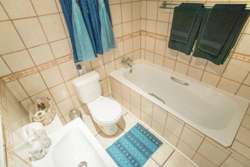 a bathroom with a tub and a toilet and a sink at Guest House Mooigezicht in Clarens