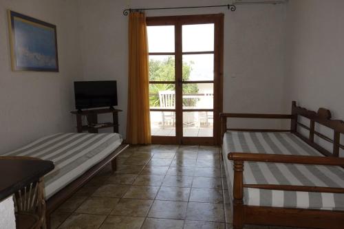 a room with two beds and a television and a window at Cretan Village Hotel in Agios Nikolaos