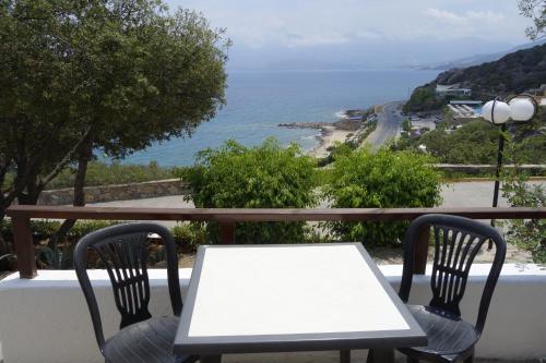 a table and chairs on a balcony overlooking the ocean at Cretan Village Hotel in Agios Nikolaos