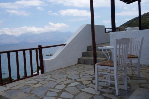 two chairs and a table on a balcony overlooking the water at Cretan Village Hotel in Agios Nikolaos
