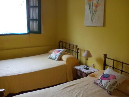 2 camas en una habitación con paredes amarillas en Cortijo El Berrocal, en Cazalla de la Sierra