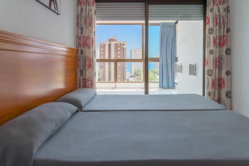 a bed in a bedroom with a large window at Gemelos 2 - Beninter All Inclusive in Benidorm