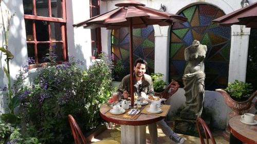a woman sitting at a table with an umbrella at Boutique Hotel Antinea in Quito