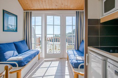 uma sala de estar com sofás azuis e uma varanda em Residence Port Bourgenay - maeva Home em Talmont