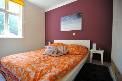 a bedroom with a bed with an orange comforter at Beutower Muhle Ferienwohnung in Beutow