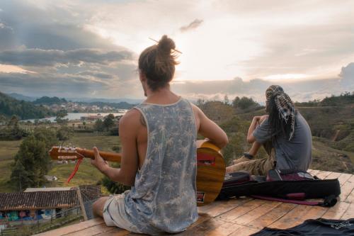 duas pessoas sentadas num telhado a tocar guitarra em Casa Kayam Hostal y Residencia Artística em Guatapé