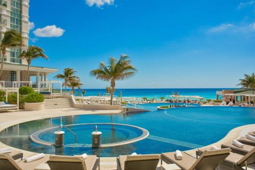 a pool with chairs and the ocean in the background at Sandos Cancun All Inclusive in Cancún