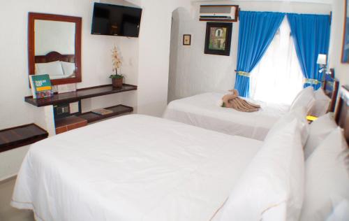 a hotel room with two beds and a mirror at Eco-hotel El Rey del Caribe in Cancún