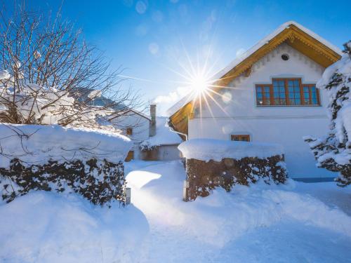 a house covered in snow with the sun behind it at Ferienwohnung Mariazell in Mariazell