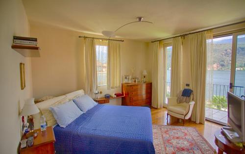 una camera con letto blu e balcone di B&B Dolce vista al lago Lugano a Porto Ceresio