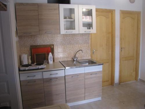 a kitchen with wooden cabinets and a sink at Heni Vend&eacute;gh&aacute;za in Vadna