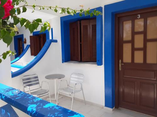 une maison avec des murs bleus et blancs, une table et des chaises dans l'établissement Paradise Studios, à Lipsi