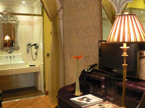una sala de estar con TV y una lámpara sobre una mesa. en Posada Real Los Cinco Linajes, en Arévalo