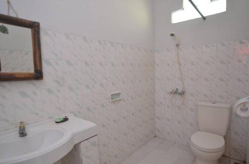 a white bathroom with a toilet and a sink at Puri Itoma Bungalows in Kuta Lombok