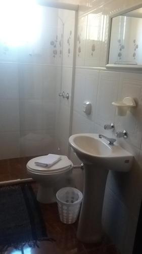 a white bathroom with a toilet and a sink at Chales Recanto das Seriemas in São Roque de Minas