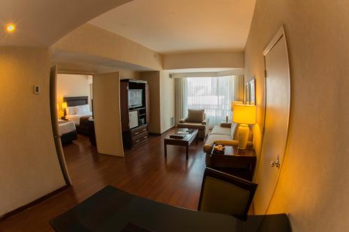 a living room with a room with a bed and a couch at Clarion Suites Guatemala City in Guatemala