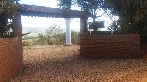 a brick wall with a gate in a yard at Chales Recanto das Seriemas in São Roque de Minas