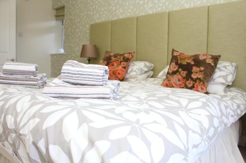 a neatly made bed with white sheets and pillows at Laurels Guesthouse in Witney