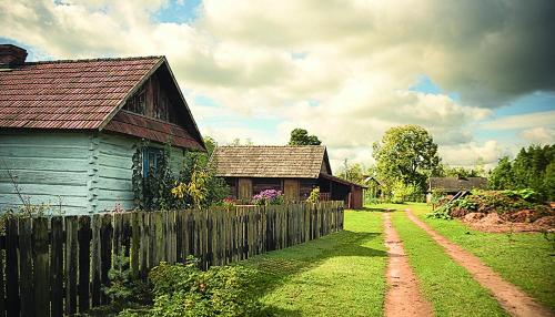 a blue barn and a wooden fence in a yard at Grenlanda in Ulanów